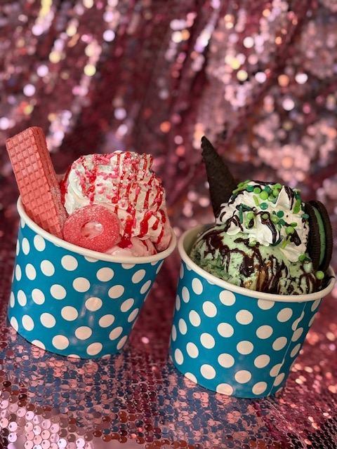 Two polka-dot cups holding a strawberry sundae and a mint sundae.
