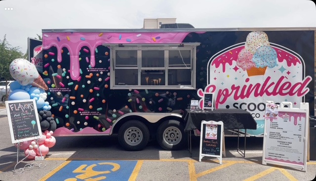 The Sprinkled Scoops Co. trailer at an event with a balloon arch and flavor chalkboard.